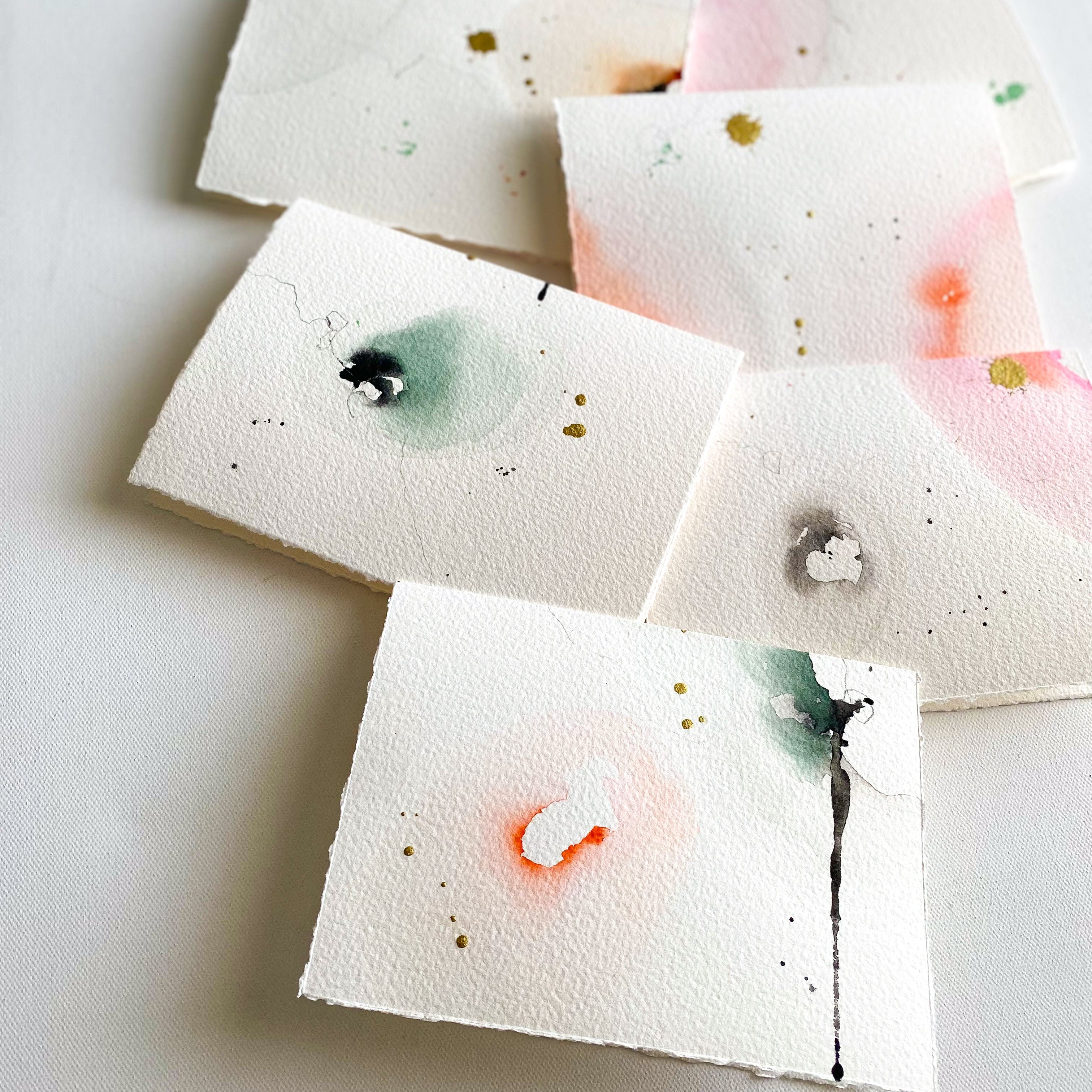 Set of watercolor cards with abstract designs on a white surface