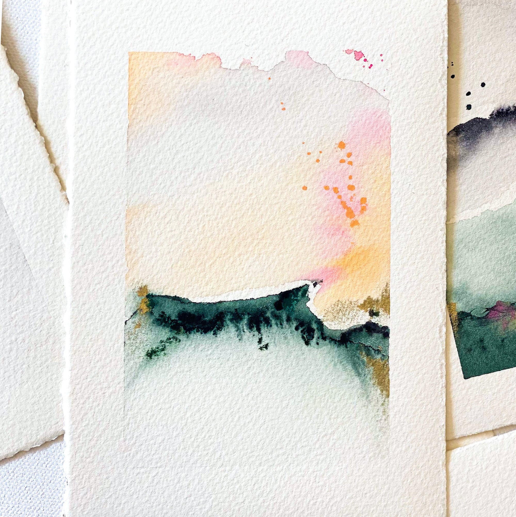 Stack of watercolor cards with abstract designs on a textured surface