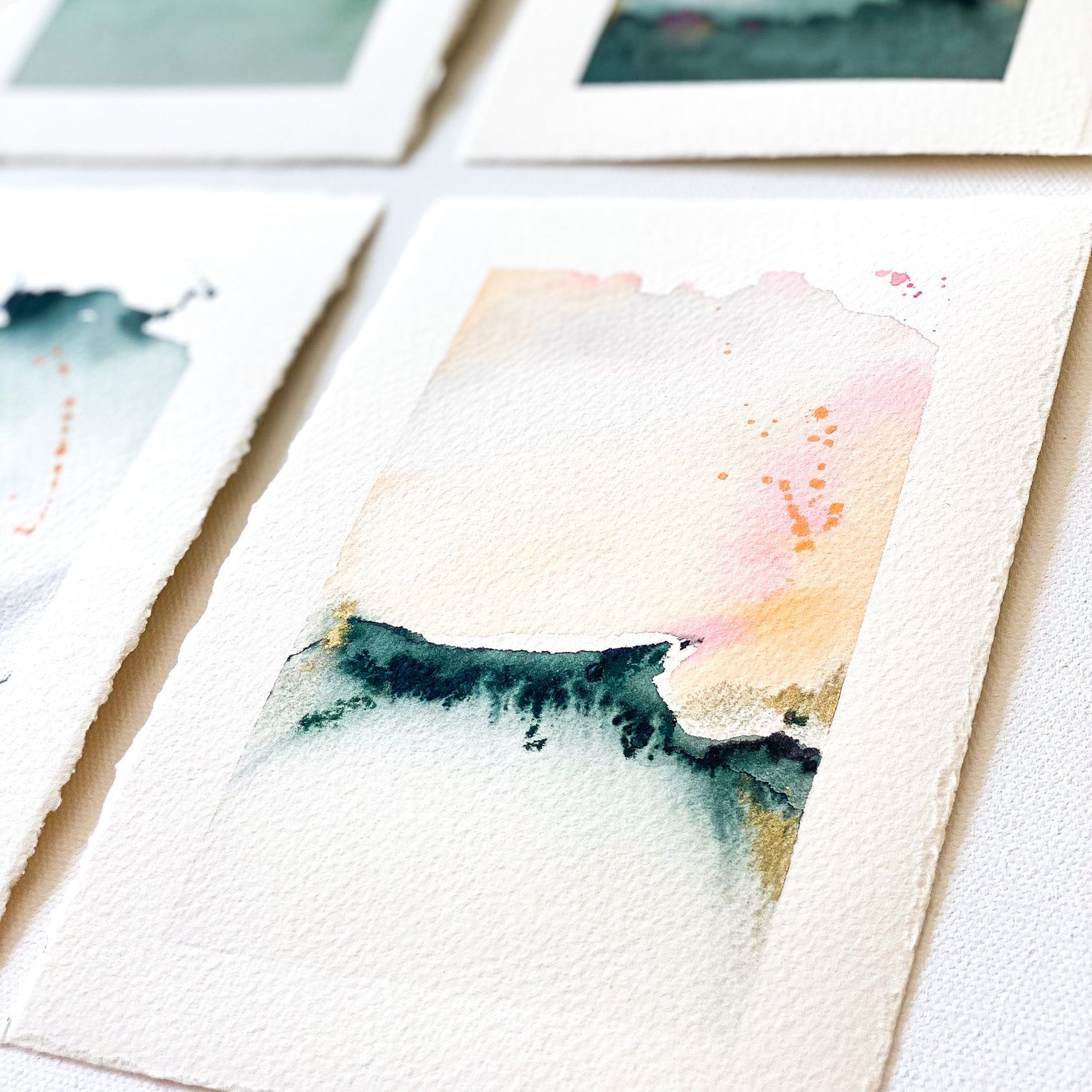 Set of watercolor cards with mountain and landscape designs on a white surface.