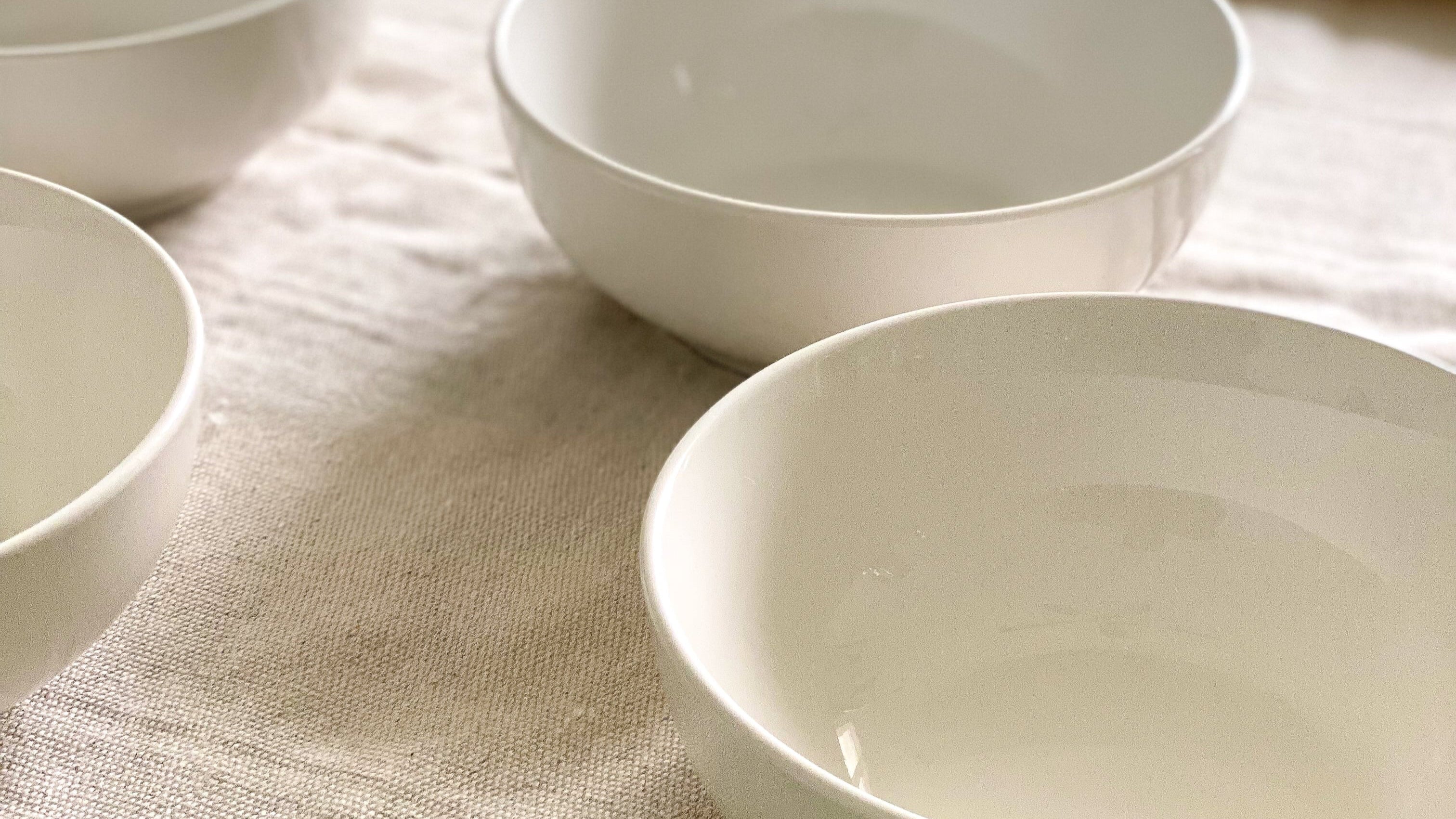 Set of white ceramic bowls on a textured fabric surface