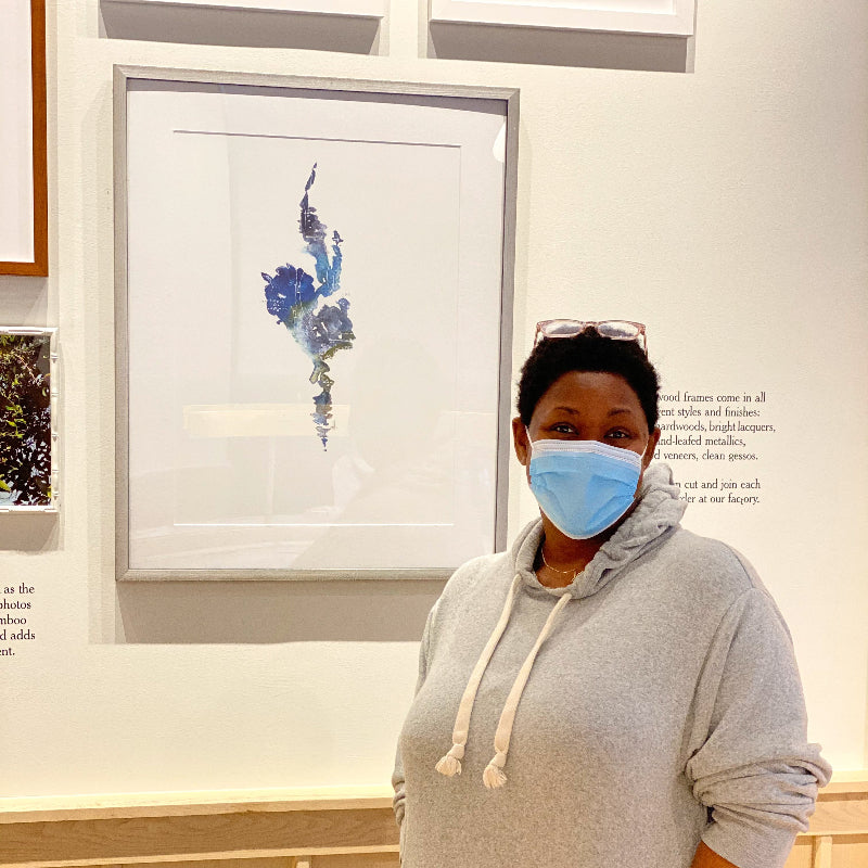 dawn m trimble  wearing a face mask standing in front of a framed picture on a wall.