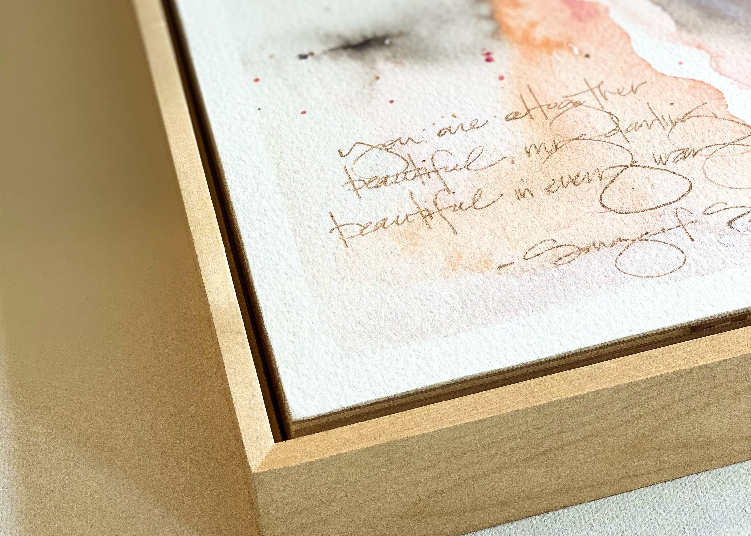 Wooden box with a watercolor painting and text on a light background