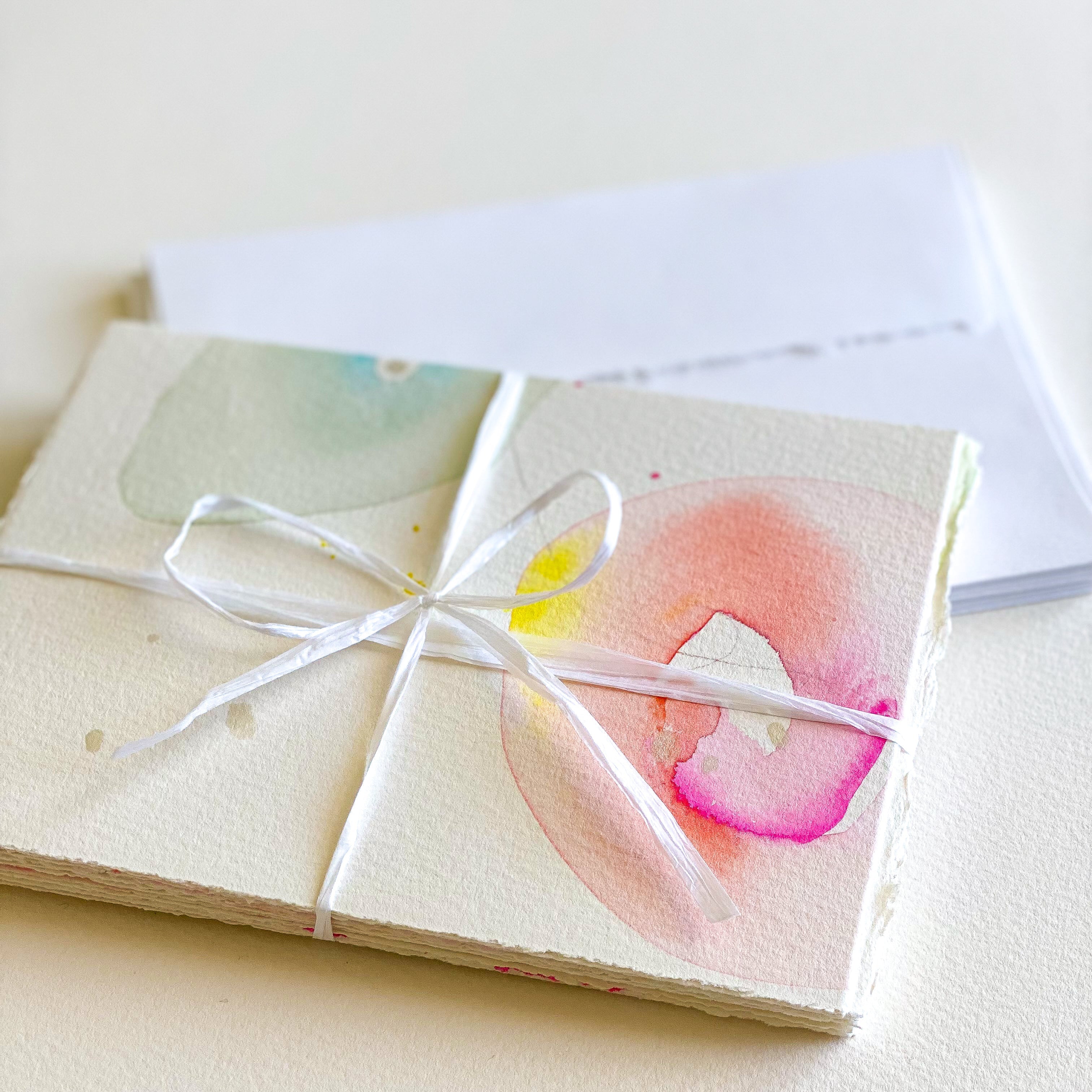 Set of watercolor cards tied with a white ribbon on a light background