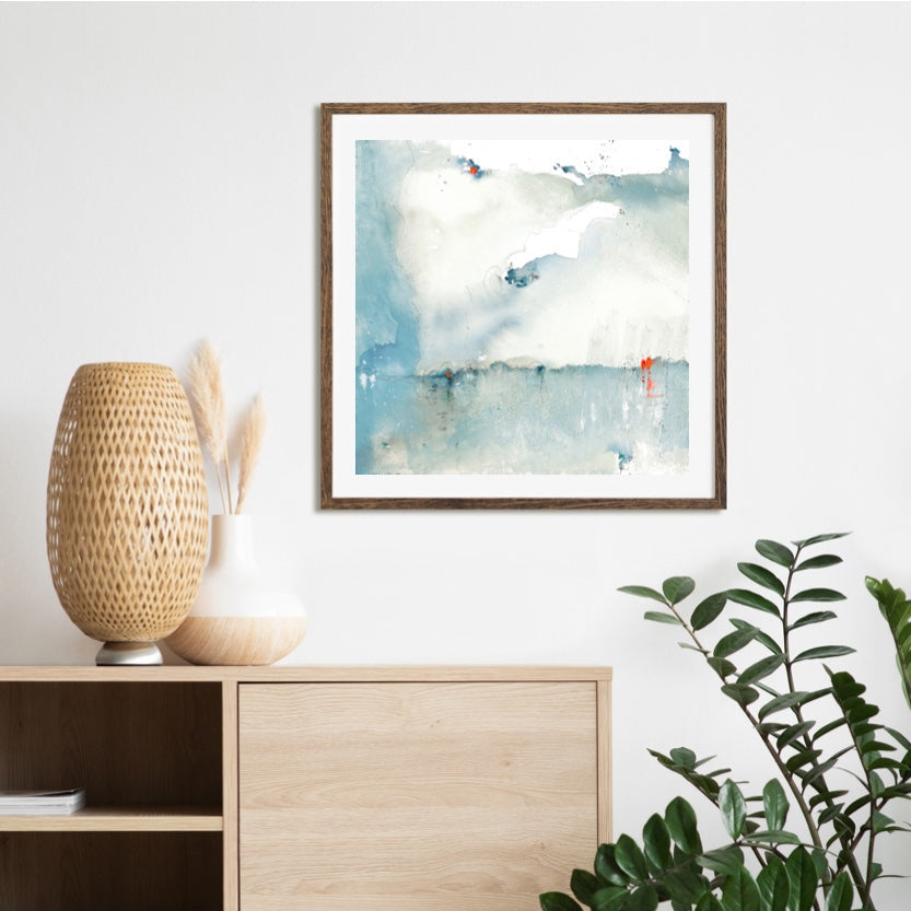 Wooden sideboard with a lamp, plant, and framed artwork in a room.