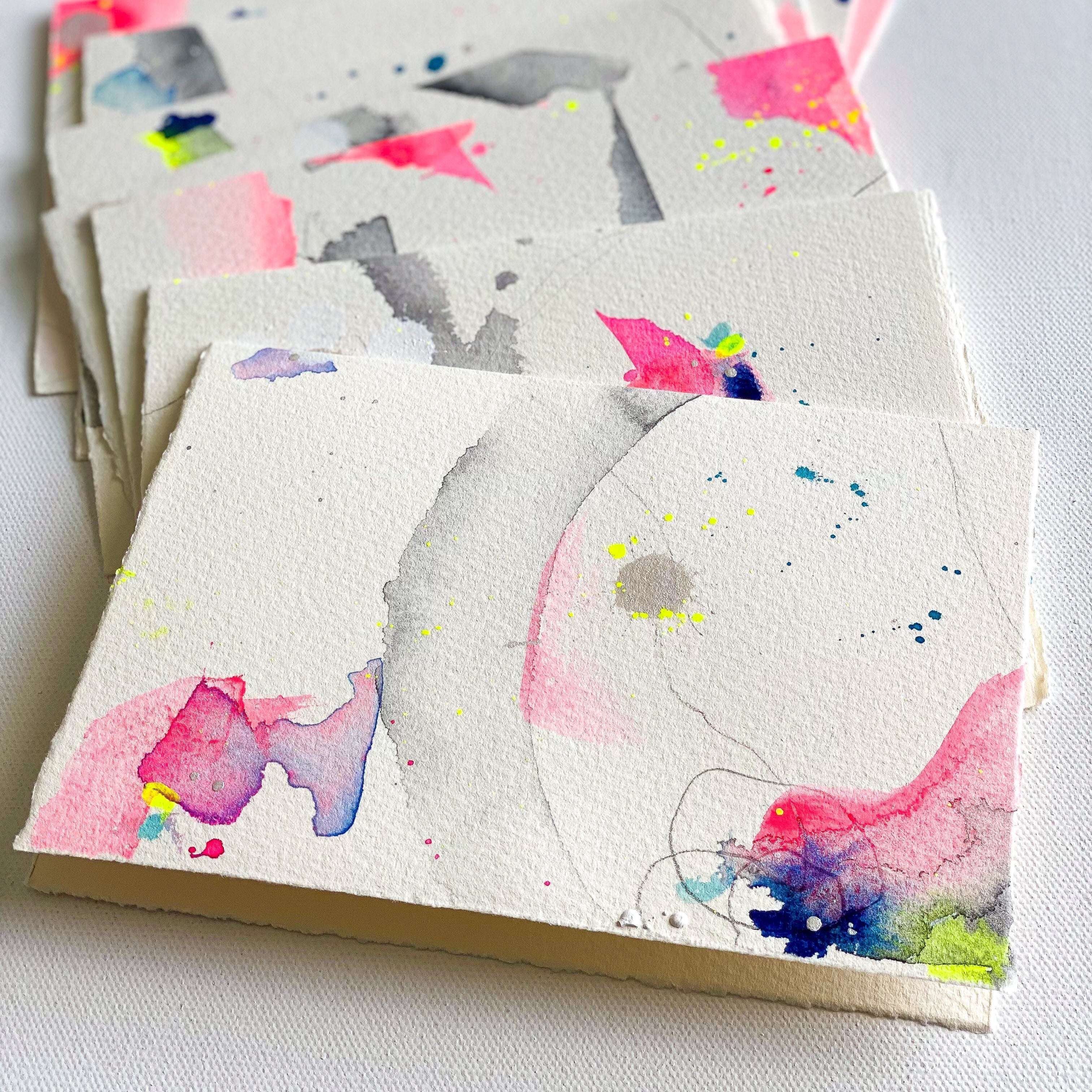 Stack of notebooks with colorful abstract designs on a white surface
