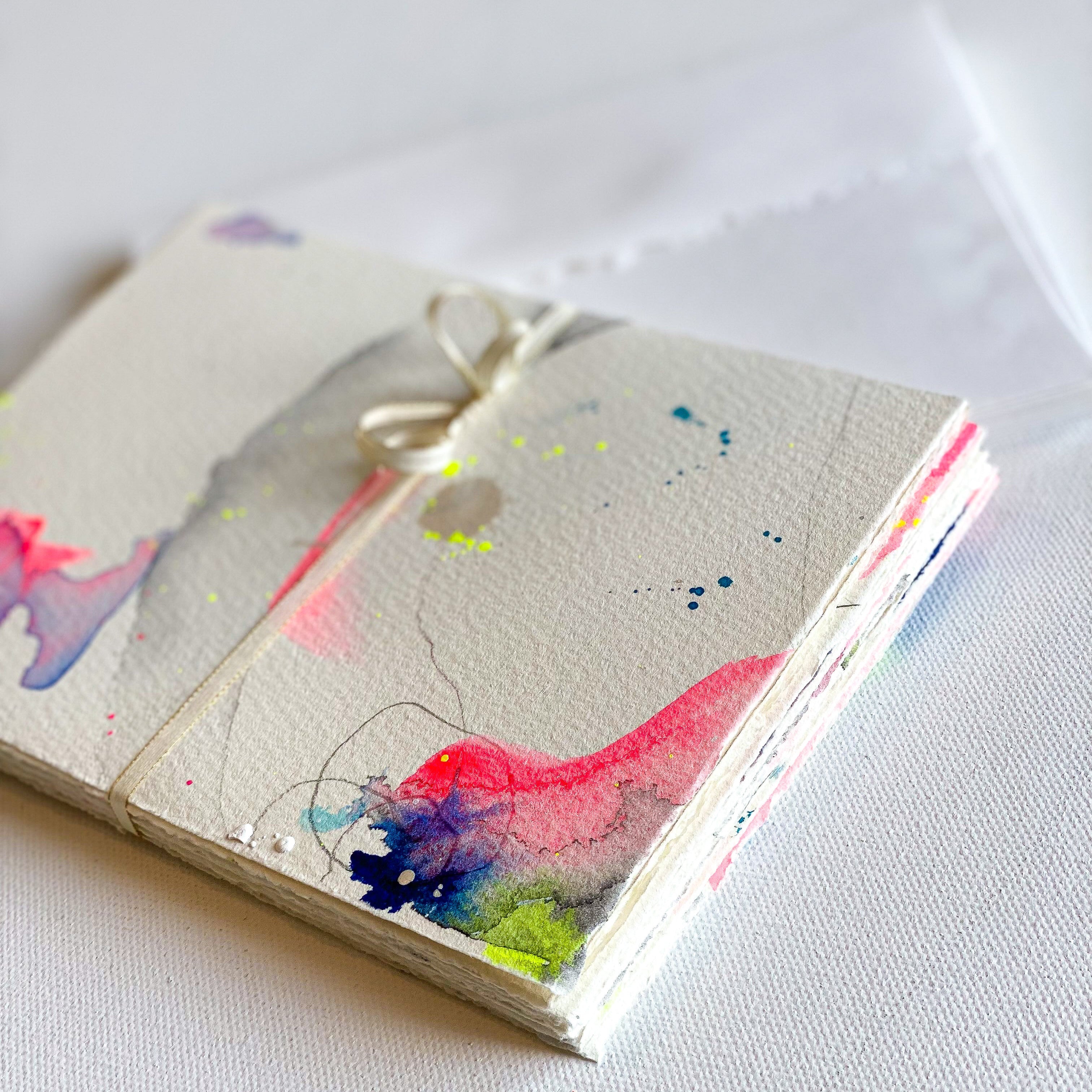 Small notebook with watercolor designs on a white surface