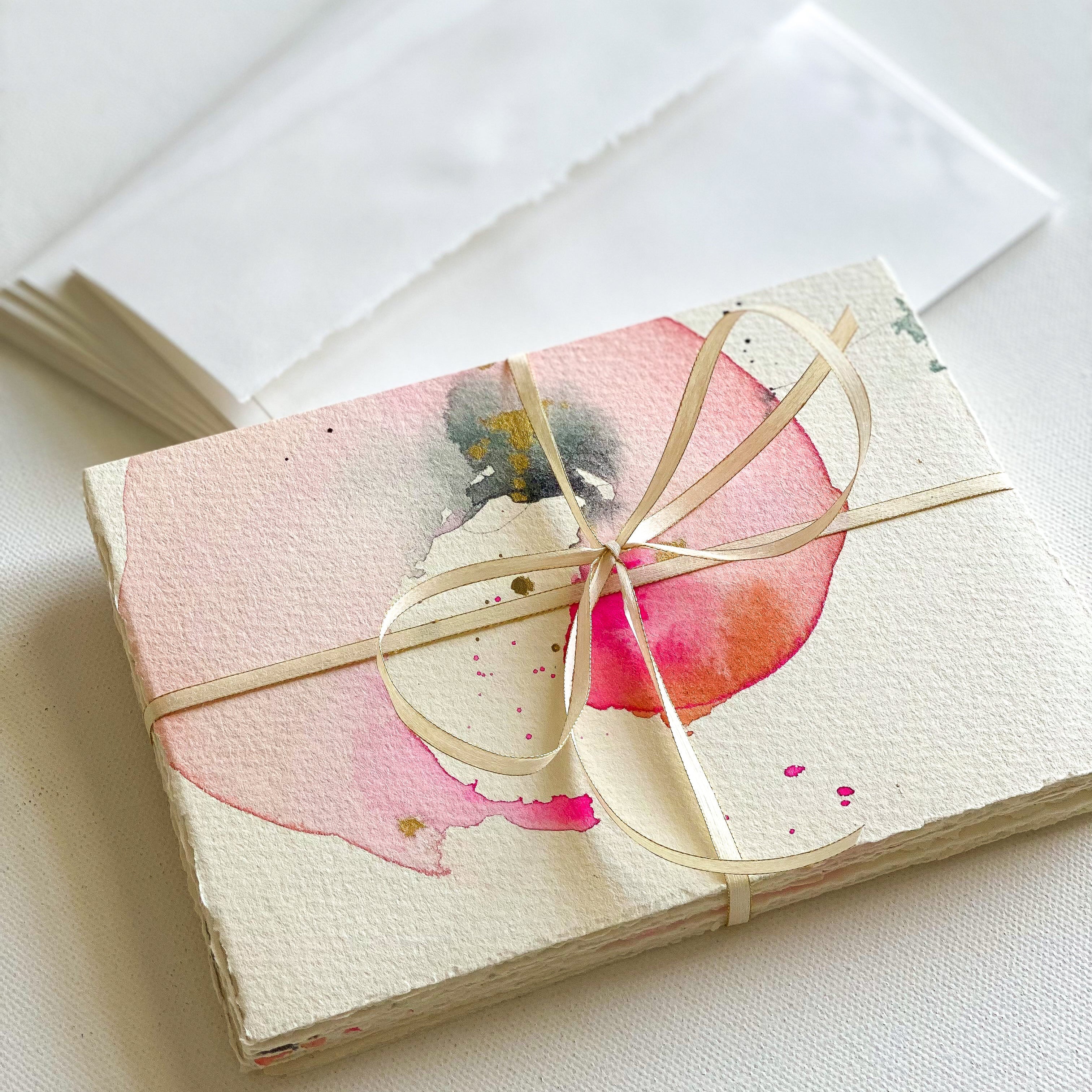 Stationery on watercolor paper with a pink flower designs on a white surface dawn trimble art