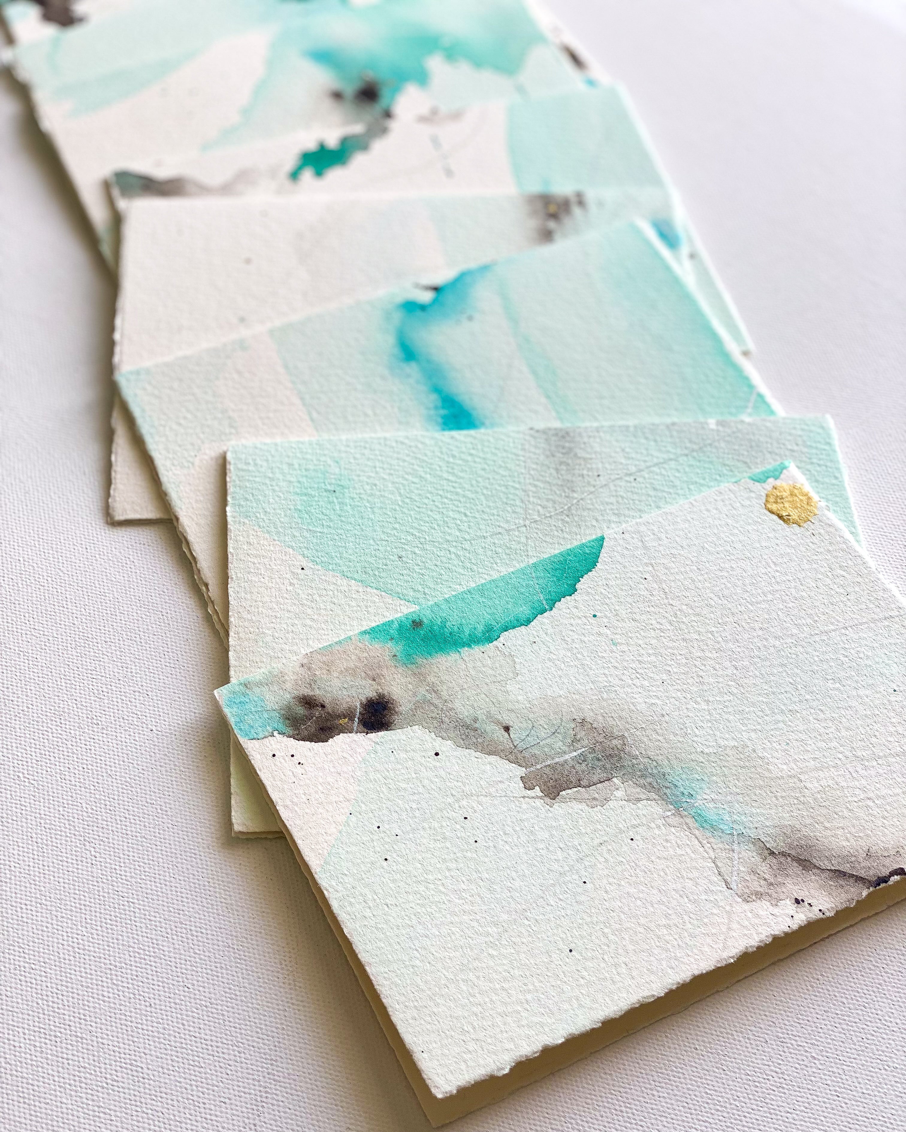 Stack of cards with watercolor designs on a light background