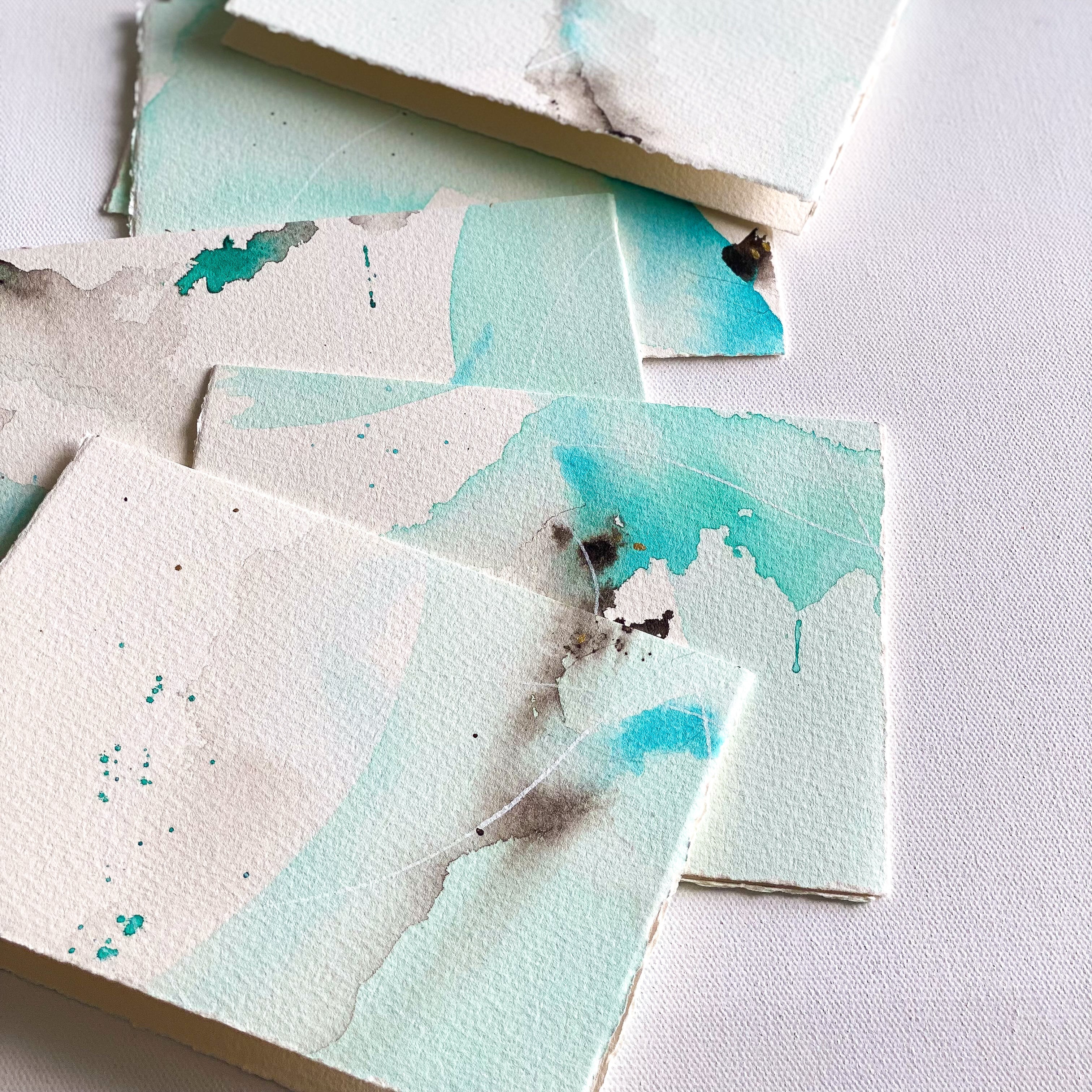 Set of square cards with watercolor designs on a white surface