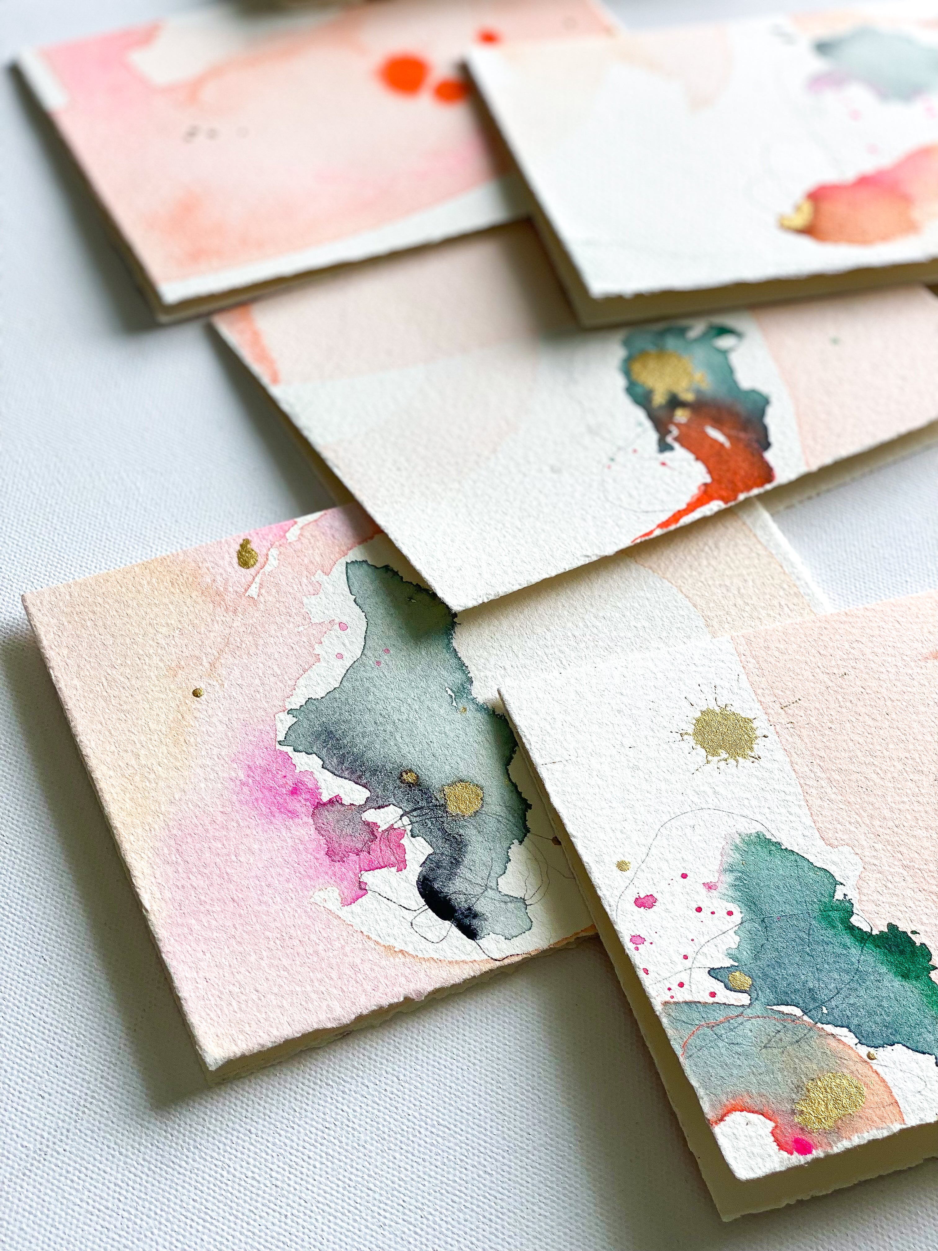 Set of small watercolor paintings on textured paper with various colors and patterns.