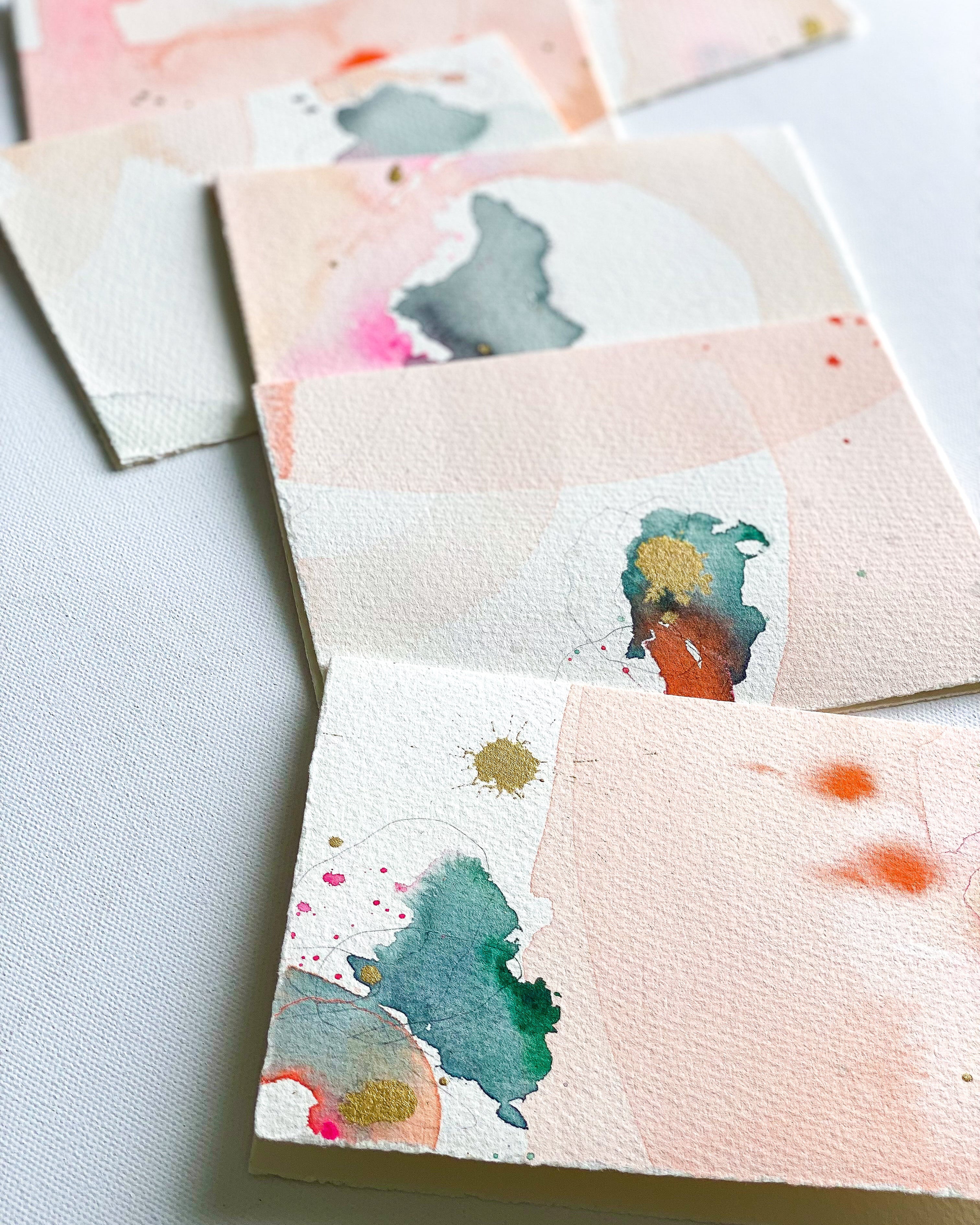 Set of watercolor cards with abstract designs on a light surface